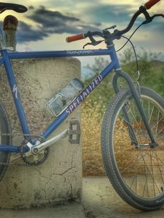 a blue bike parked next to a cement wall with the word specialized written on it