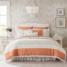 an orange and white bed in a bedroom with floral wallpaper on the walls behind it