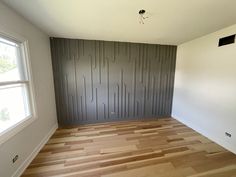 an empty room with hard wood flooring and gray wall paneling in the corner