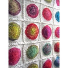 a crocheted wall hanging with many different colored balls on it's side