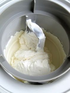 a mixing bowl filled with white cream on top of a counter