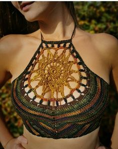 a woman wearing a crocheted top with an intricate design on it's chest