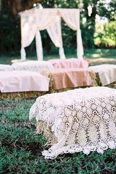 an outdoor wedding ceremony with pink and white linens on the grass, covered in lace