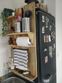 a kitchen area with a refrigerator, sink and various utensils on the shelves