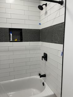 a white bath tub sitting next to a black and white tiled wall