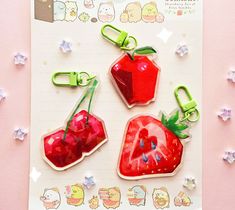 three strawberry shaped magnets on top of a piece of paper