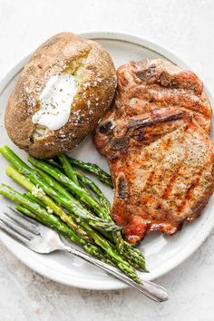 a white plate topped with meat and asparagus