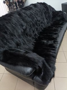 a large black furry animal laying on top of a leather couch