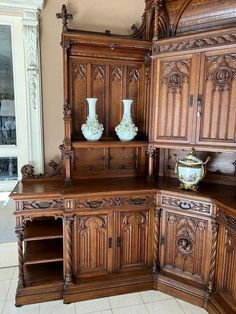 an ornate wooden cabinet with two vases on the top and bottom shelf in front of it