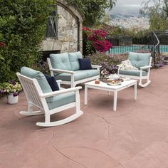 three chairs and a table sitting on top of a patio next to a swimming pool