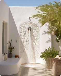 an outdoor shower in the middle of a patio with potted plants next to it