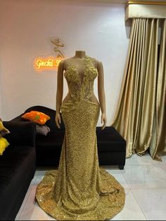 a mannequin is dressed in gold sequins and stands next to a couch