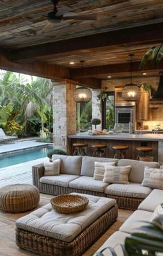 an outdoor living area with couches and tables next to a pool in the background