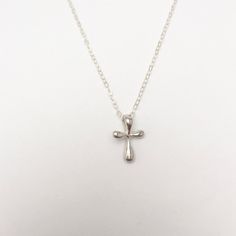 A gorgeous tiny and simple, Sterling Silver cross hangs delicately from a Sterling Silver chain. This small, slightly puffy cross has softly rounded edges and is super smooth. Available in Sterling Silver or Gold Vermeil. A beautiful keepsake piece of jewelry or gift for a baptism or dedication that will last a lifetime. - Pendant - Sterling Silver or Gold Vermeil - 13mm x 9mm (Made in the USA) - Chain + components - Sterling Silver or 14K Gold-Fill - Clasp - Sterling Silver or 14K Gold-filled l Affordable Silver Cross Pendant Jewelry, Small Silver Cross Necklace, Minimalist Cross Charm Necklace With Delicate Chain, Minimalist Cross Charm Necklace With Adjustable Chain, Dainty Cross Necklace For Baptism, Sterling Silver Cross Necklace For Baptism, Minimalist Cross Pendant Necklaces For Baptism, Minimalist Cross Pendant Necklace For First Communion, Minimalist Cross Pendant Necklace For Baptism