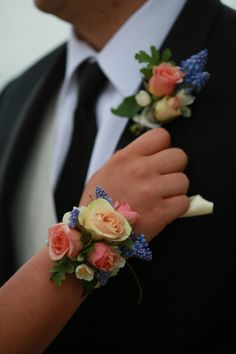 a man and woman wearing boutonnieres with flowers on their wrists in front of each other