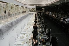 a long table with white flowers and candles is set for a formal dinner or banquet