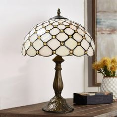 a lamp sitting on top of a wooden table next to a vase with yellow flowers