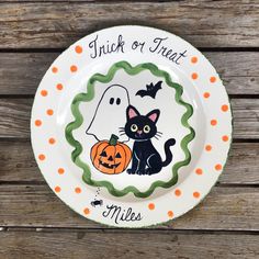 a white plate with a black cat and a ghost on it that says, trick or treat miles