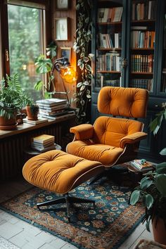 an orange chair and ottoman in front of a book shelf with books on it next to a window