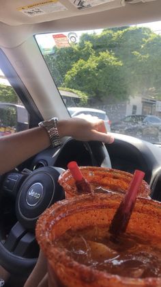 two people driving in the back seat of a car with food on the rims