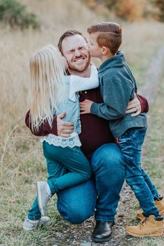 a man and woman hug their son as they stand in the middle of a field