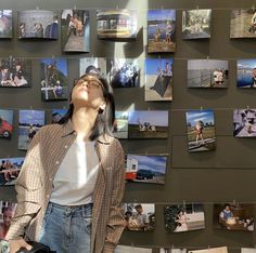 a woman standing in front of a wall with pictures on it