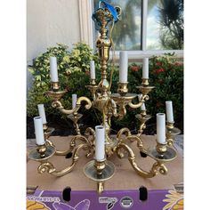 a gold candelabra with white candles on it in front of a window