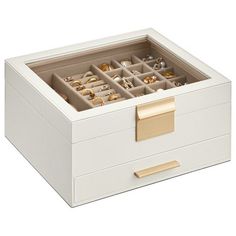 a white box with many compartments and gold handles on the lid is open to reveal jewelry