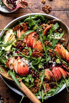 an apple salad with spinach, pecans and cranberries in a bowl