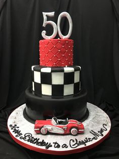 a 50th birthday cake with a red car on the front and white checkered design