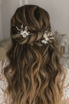 a woman with long wavy hair wearing a flowered headpiece in her left hand