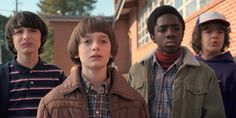 three young boys standing in front of a building with one looking up at the camera