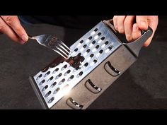 a person holding a fork and knife over a metal grater