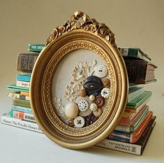 there is a gold frame with buttons in it on top of many books and magazines