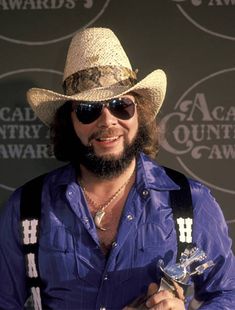 a man in a cowboy hat and sunglasses holding an award