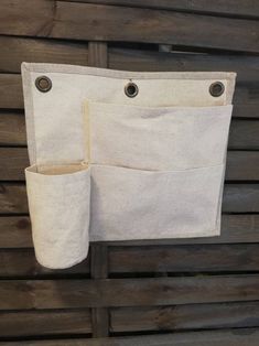 a white bag hanging on the side of a wooden wall with two pockets in it