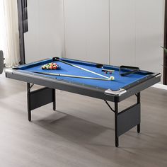 a blue pool table with cues and balls on it in front of a white wall