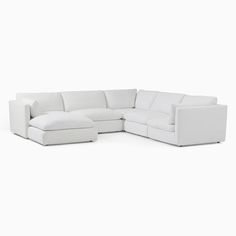 a white sectional couch sitting on top of a white floor next to a chair and ottoman