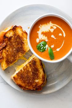 grilled cheese and tomato soup with toasted bread on a white plate, ready to be eaten