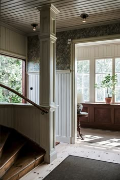 an open door leading to a living room with stairs and potted plant in the corner