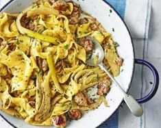 a bowl filled with pasta and meat on top of a blue and white table cloth