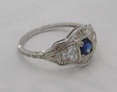 an antique style ring with blue and white stones on the sides, set in silver