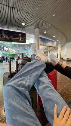 two people sitting in chairs with their feet on each other's legs at an airport