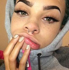 a woman with fake eyebrows and piercings on her nose is posing for the camera