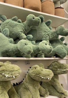 several stuffed alligators are on shelves in a store, one is green and the other is brown