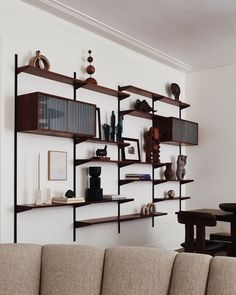 a living room filled with lots of furniture and shelves on the wall next to a couch