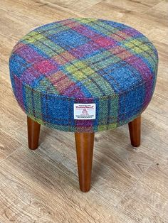 a multicolored foot stool sitting on top of a wooden floor