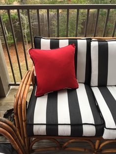 a black and white striped chair with red pillow on it's backrests