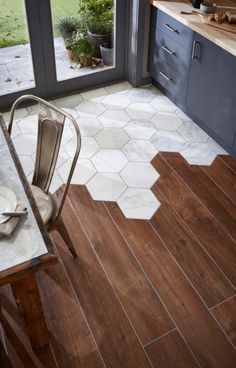 a kitchen with wooden flooring and white hexagonal tiles on the floor next to a window