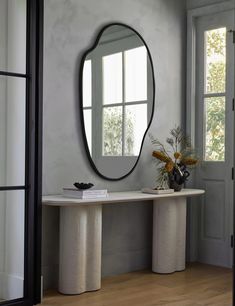 an oval mirror on the wall above a console table